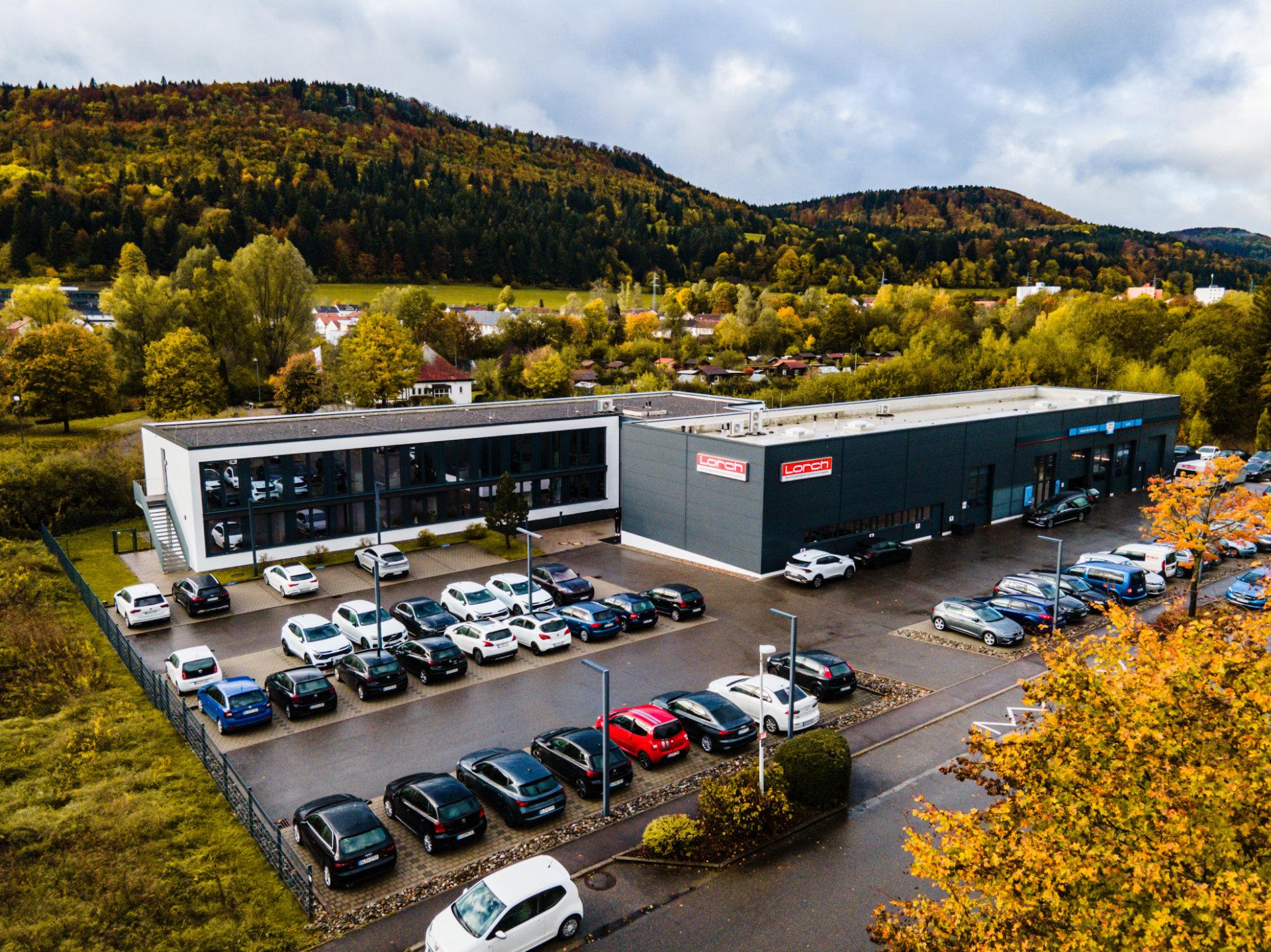 Die Lorch Vertriebszentral in einem weiteren Ausschnitt mit dem gesamten Parkplatz und dem grünen Wald im Hintergrund